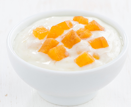 Image of yoghurt in a bowl topped with chopped peaches