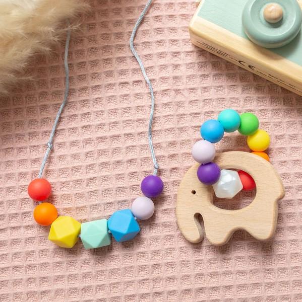 A teething necklace and wooden elephant, both with rainbow coloured silicone beads.