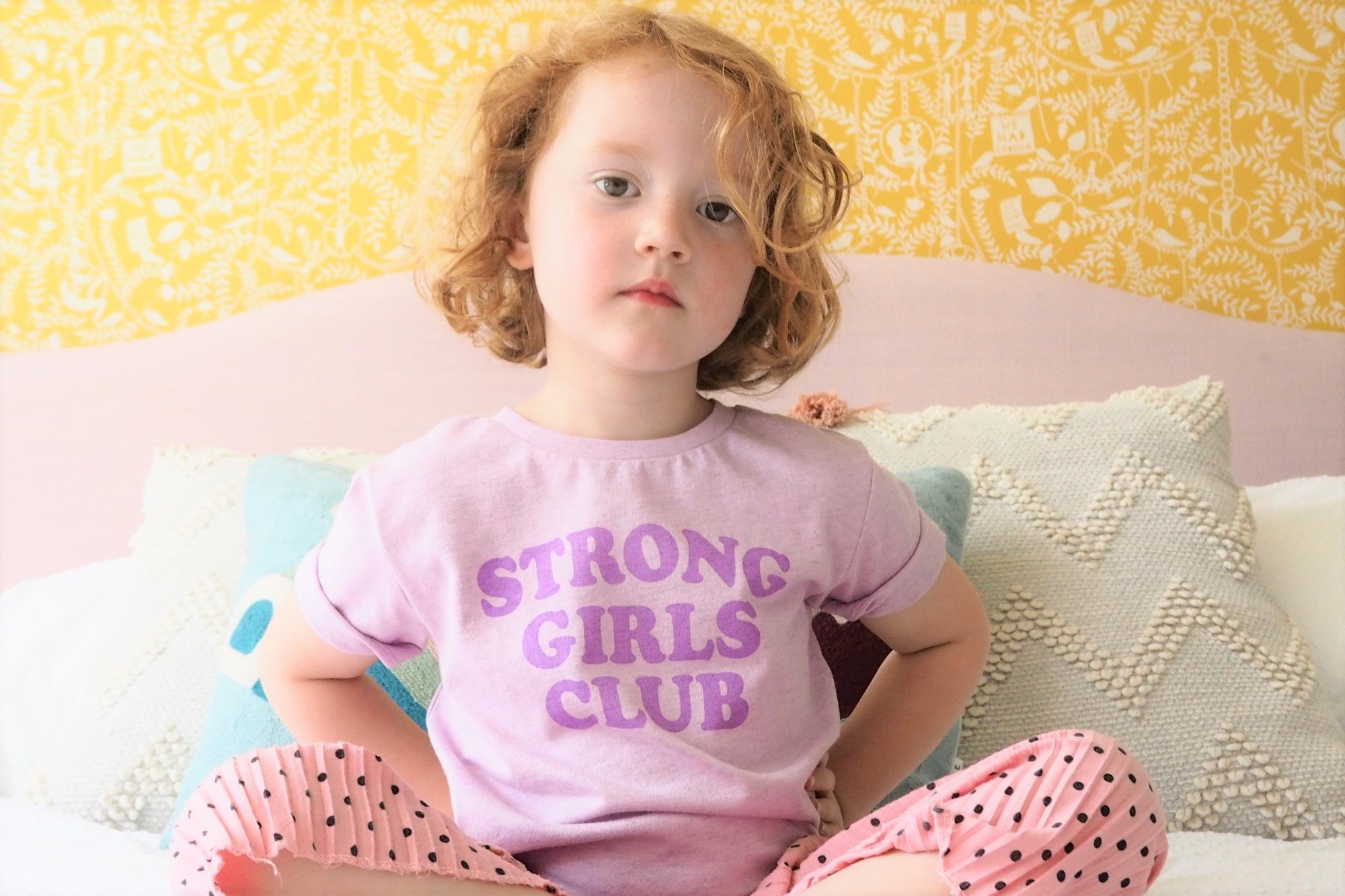 A young girl modelling a lilac t-shirt with the words Strong Girls Club on