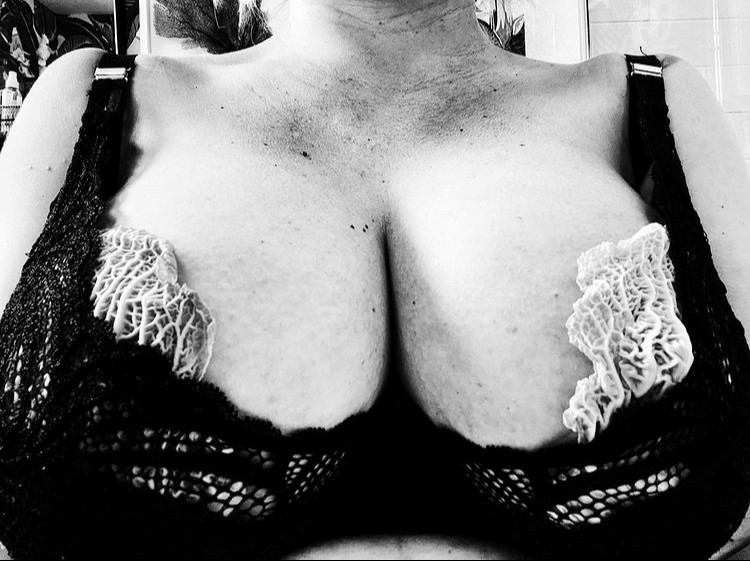 Black and white image of Paloma Faith's breasts, she is wearing a black bra with cabbage leaves in the cups