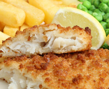 Close up image of fish and chips with peas and lemon wedge