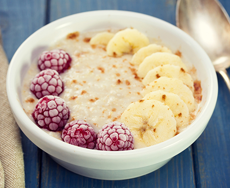 Image of porridge bowl with frozen raspberries and banana on top 