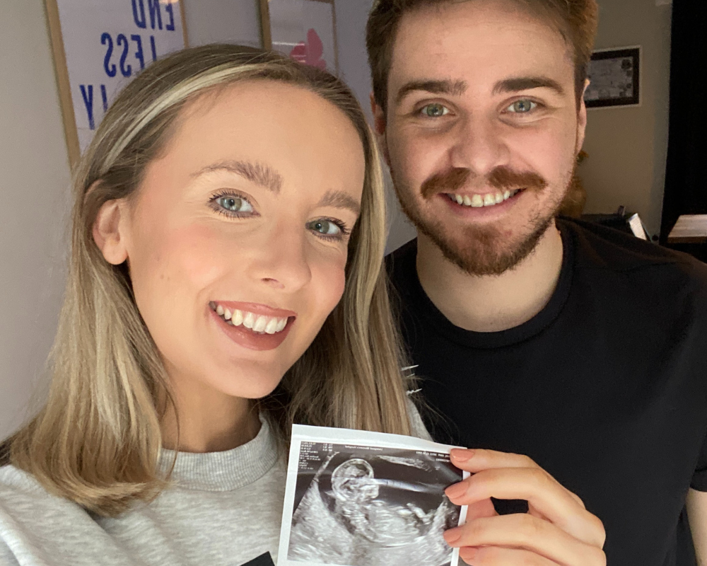 Amy and her partner holding a scan of their baby