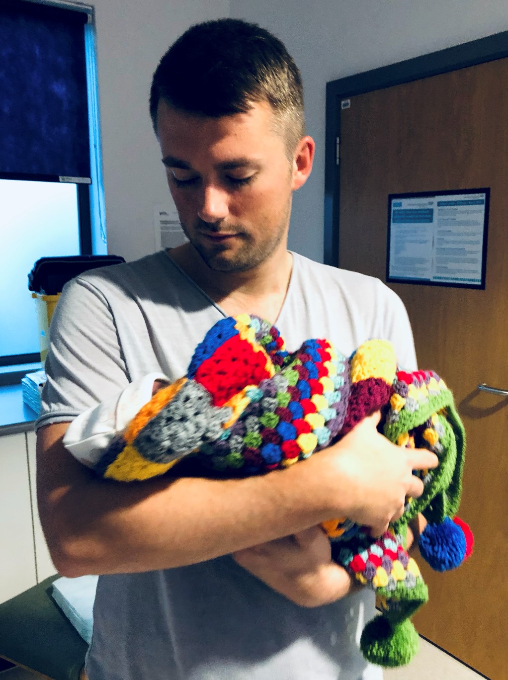 Ross holds his stillborn son Leo, who is wrapped in a colourful homemade blanket
