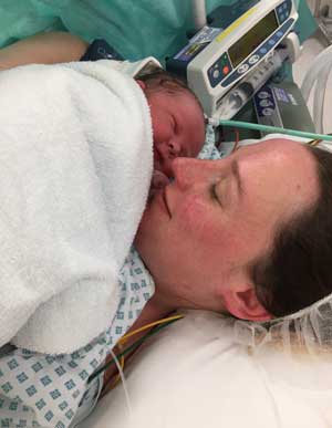 A photo of Annie laying on the hospital bed holding newborn Monty to her chest after a c-section