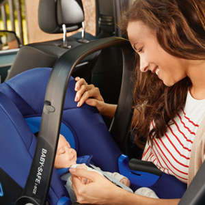 Photo of a newborn baby in a car seat with his mum looking at him