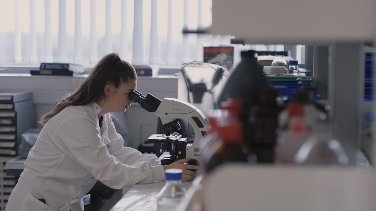 A female researcher looking into a microscope at Tommy's National Centre for Miscarriage Research